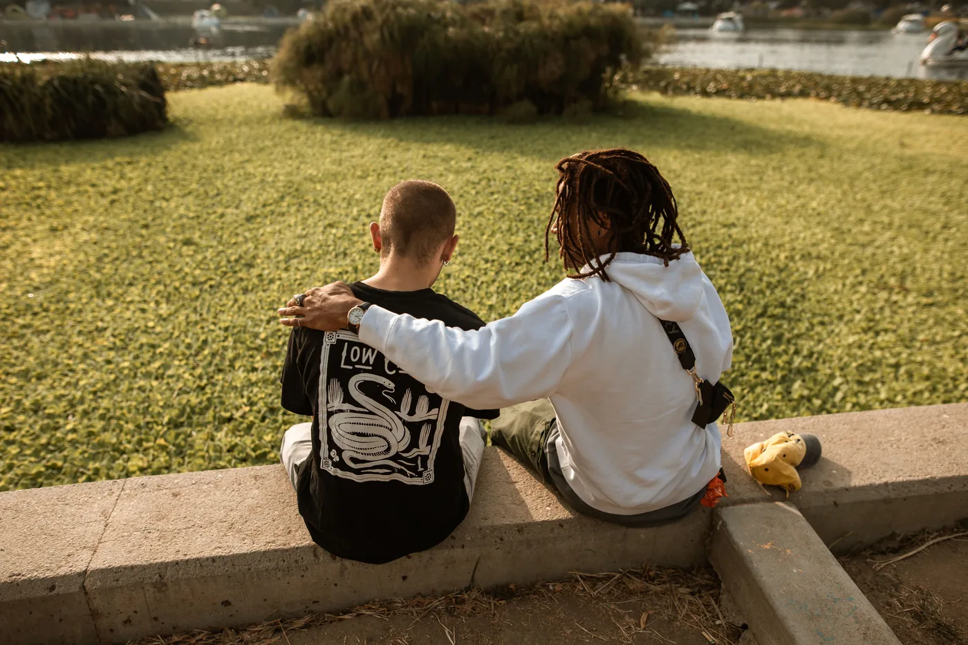 Two friends sitting outside, one offering a supportive arm around the other
